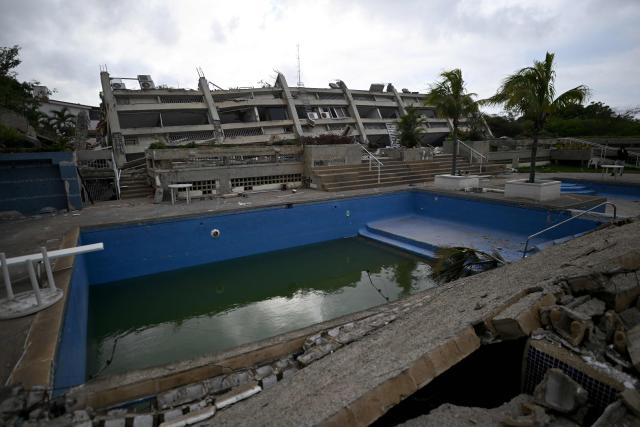 Collapsed structures and a damaged swimming pool are seen at a residential complex in Caraballeda, La Guaira state, Venezuela, on June 30, 2026, following twin earthquakes that struck the coastal region. Tens of thousands of people desperately sought food and shelter in Venezuela on June 30 after the two earthquakes killed nearly 2,000, but rescue teams managed to pull a 3-year-old boy alive from the rubble six days after the shocks. (Photo by Juan BARRETO / AFP)