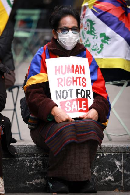 A member of the Australian Tibetan community wears a mask as she holds a placard during a protest in Sydney on July 1, 2026. (Photo by DAVID GRAY / AFP)