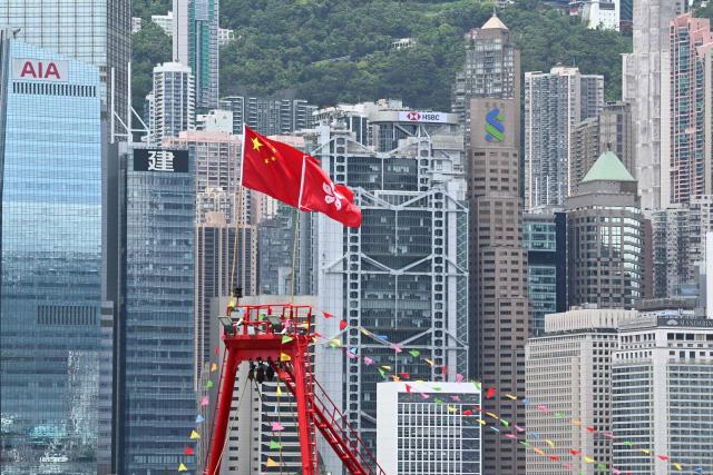 The China (L) and Hong Kong flags are seen on top of a fishing boat as it sails through Victoria Harbour to mark the 29th anniversary of Hong Kong's handover from Britain to China, in Hong Kong on July 1, 2026. (Photo by Peter PARKS / AFP)