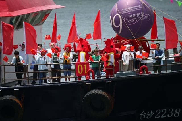 People on a fishing boat wave China and Hong Kong flags as they sail through Victoria Harbour to mark the 29th anniversary of Hong Kong's handover from Britain to China, in Hong Kong on July 1, 2026. (Photo by Peter PARKS / AFP)
