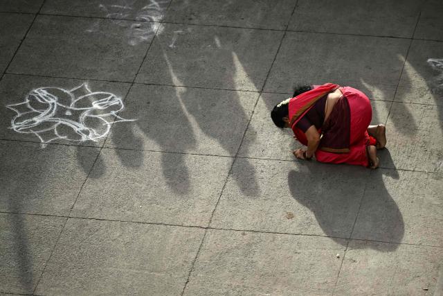 A woman seeks a blessing from the group of priests, who take part by chanting mantras in a chariot festival of Sri Parthasarthy Temple in Chennai on July 1, 2026. (Photo by R. Satish BABU / AFP)