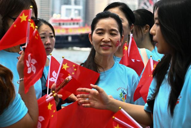People wave China and Hong Kong flags to mark the 29th anniversary of Hong Kong's handover from Britain to China, in Hong Kong on July 1, 2026. (Photo by Peter PARKS / AFP)