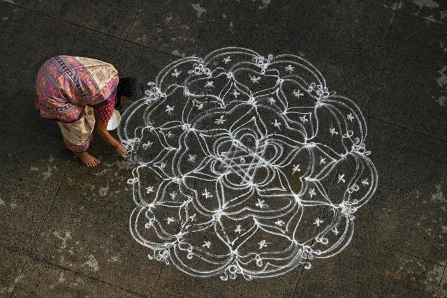 A Hindu devotee draws Kolam during the chariot festival of Sri Parthasarathy Temple in Chennai on July 1, 2026. (Photo by R. Satish BABU / AFP)