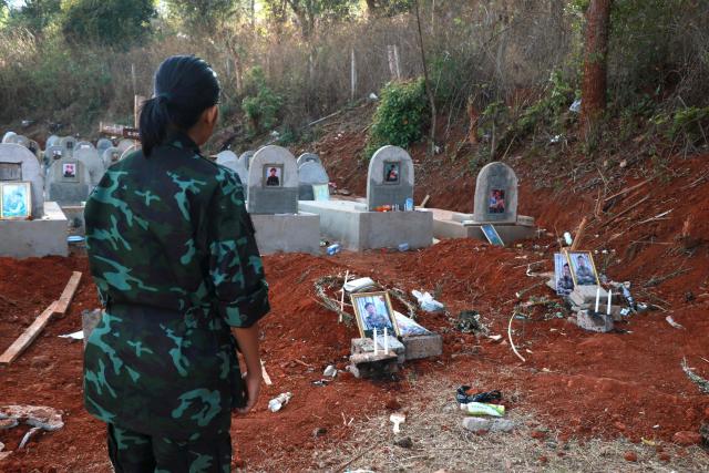 (FILES) This photo taken on March 6, 2025 shows an Urban Revolution Front (URF) soldier in front of gravestones of two URF soldiers killed by a Myanmar military drone attack in the forest near Moe Bye in Myanmar's eastern Shan State. More than 100,000 people have been killed across all sides in Myanmar since a military coup five years ago triggered civil war, a conflict monitor said July 1, 2026. (Photo by AFP)