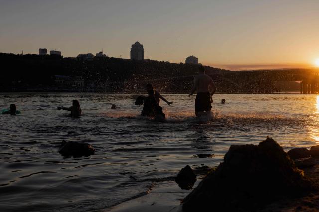 People swim in the Dnipro River during a hot summer’s day in Kyiv on June 30, 2026, amid the Russian invasion of Ukraine. (Photo by Tetiana DZHAFAROVA / AFP)