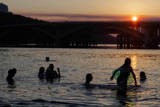 People swim in the Dnipro River during a hot summer’s day in Kyiv on June 30, 2026, amid the Russian invasion of Ukraine. (Photo by Tetiana DZHAFAROVA / AFP)