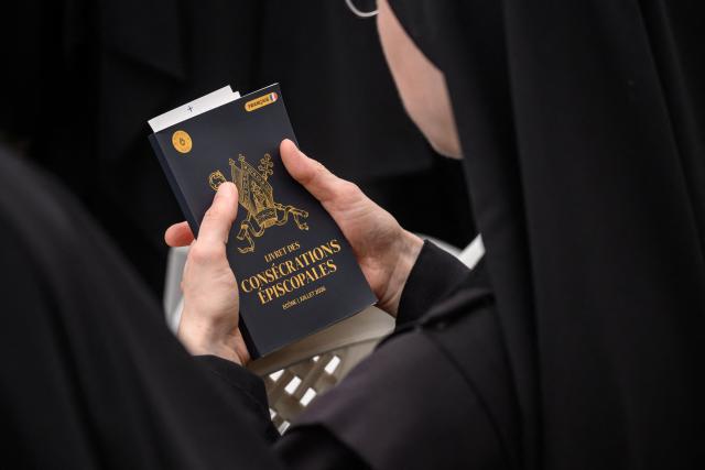 A nun hold a book of Episcopal Consecrations during the schismatic consecration of bishops by the traditionalist Catholic Society of Saint Pius X (SSPX) in Econe, western Switzerland, on July 1, 2026. The Society of Saint Pius X consecrated four new bishops on July 1, 2026, in defiance of Pope Leo XIV, who pleaded with the ultra-traditionalist breakaway group to turn back from what he called a "schismatic act" with Rome. (Photo by Fabrice COFFRINI / AFP)
