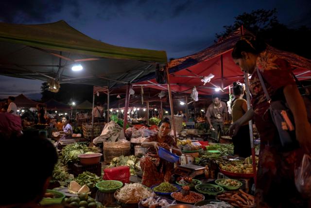 This photo taken on June 1, 2026 shows people buying vegetables at a night market in Naypyidaw. (Photo by Sai Aung MAIN / AFP)