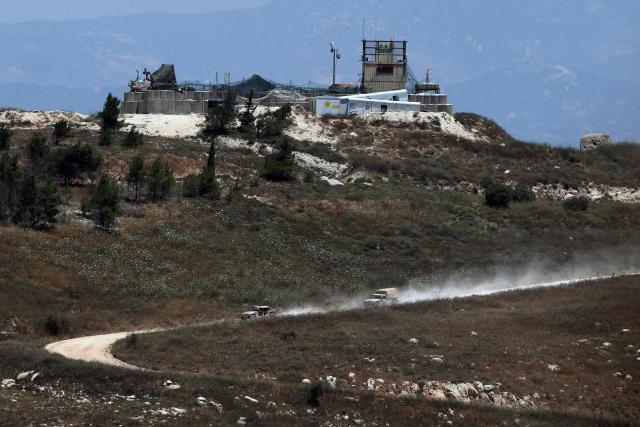 This picture taken from a position in the Upper Galilee in northern Israel shows Israeli military vehicles driving past houses destroyed in Israeli strikes in the southern Lebanese village near the Israel-Lebanon border, on July 1, 2026. Israel's defence minister said on July 1 that Israeli forces would remain in self-proclaimed "security zones" established in Lebanon, Syria and Gaza, without any timeline for withdrawal. (Photo by Jack GUEZ / AFP) / 