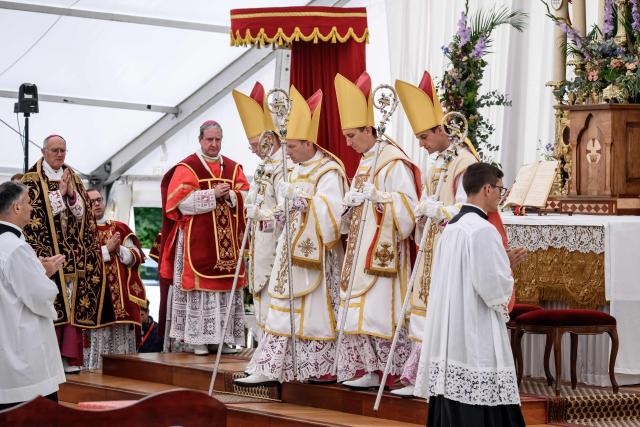 (From L) The new traditionalist Catholic consacred bishops Swiss Pascal Schreiber, US' Michael Goldade, French Michel Poinsinet de Sivry and French Marc Hanappier walk past Spanish born traditionalist Catholic Bishop of the Society of Saint Pius X (SSPX) Alfonso de Galarreta during the schismatic consecration of bishops by the traditionalist Catholic Society of Saint Pius X (SSPX) in Econe, western Switzerland, on July 1, 2026. The Society of Saint Pius X consecrated four new bishops on July 1, 2026, in defiance of Pope Leo XIV, who pleaded with the ultra-traditionalist breakaway group to turn back from what he called a "schismatic act" with Rome. (Photo by Fabrice COFFRINI / AFP)