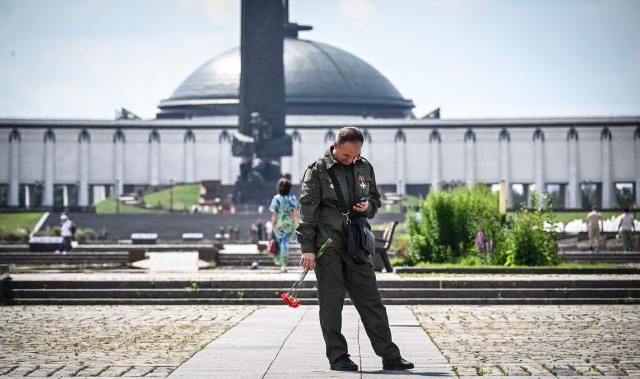 A Russian veteran of the Russian-Ukrainian conflict holding red carnations looks onto his smartphone outside the Museum of the Great Patriotic War (also known as the Victory Museum ) at Poklonnaya Hill in western Moscow on July 1, 2026. Russia fired fewer drones and missiles at Ukraine in June compared to a month before, an AFP analysis of Ukrainian air force data showed Wednesday, as Kyiv stepped up its own retaliatory attacks on Russia. (Photo by Alexander NEMENOV / AFP)