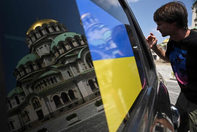 A Bulgarian donor looks inside ? donated car with a Ukrainian flag on the window during a ceremony to hand over 17 off-road vehicles donated by Bulgarians and Russians living in Bulgaria, in front of the Alexander Nevsky Cathedral in Sofia on July 01, 2026. (Photo by Nikolay DOYCHINOV / AFP)