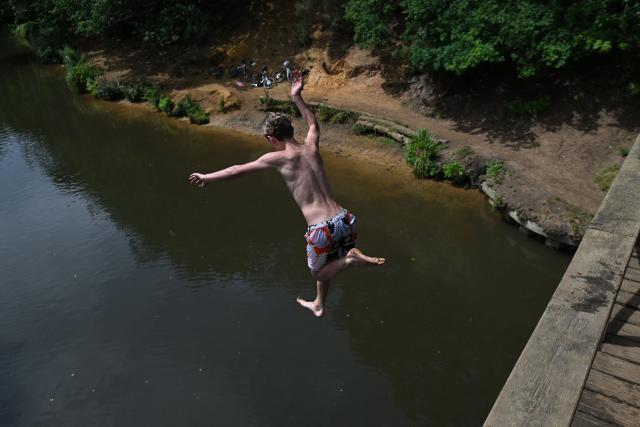 (FILES) A youngster cools off by leaping from the Wey footbridge into the River Wey, near Guildford, south of London on June 27, 2026, during a heatwave. England chalked up its warmest June since records began in 1884, the Met Office weather service said on on July 1, 2026, after a month that saw temperatures soar to new highs. (Photo by JUSTIN TALLIS / AFP)