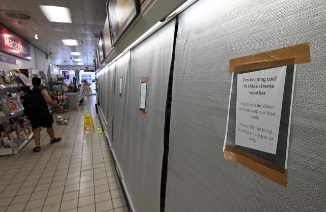 (FILES) Signs on blinds covering fridges in the chilled food aisle of a Sainsbury's supermarket, alert customers that they have been pulled down to keep food cool during the extreme heat, in Guildford, on the south coast of England on June 25, 2026, during a heatwave. England chalked up its warmest June since records began in 1884, the Met Office weather service said on on July 1, 2026, after a month that saw temperatures soar to new highs. (Photo by JUSTIN TALLIS / AFP)