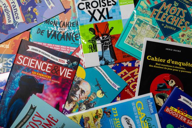This photograph taken in Paris on June 30, 2026 shows various vacation workbooks for adults. (Photo by JOEL SAGET / AFP)