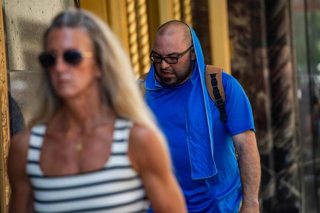 A man walks with a towel draped over his head and neck during a heat wave in Boston, Massachusetts on July 1, 2026. Tens of millions of Americans sweltered under furnace-like temperatures this week as central and eastern cities hunkered down for a heat wave set to last through the July 4 holiday weekend. Dozens of local temperature records could be broken, the National Weather Service (NWS) warned, with temperatures in many places to surpass 100 degrees Fahrenheit (38 degrees Celsius) and high humidity pushing the heat index as high as 115 degrees. (Photo by Joseph Prezioso / AFP)
