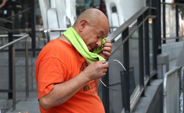 A person wipes his face outside Madison Square Garden during a heatwave in New York on July 1, 2026. Tens of millions of Americans sweltered under furnace-like temperatures this week as central and eastern cities hunkered down for a heat wave set to last through the July 4 holiday weekend. Dozens of local temperature records could be broken, the National Weather Service (NWS) warned, with temperatures in many places to surpass 100 degrees Fahrenheit (38 degrees Celsius) and high humidity pushing the heat index as high as 115 degrees. (Photo by TIMOTHY A. CLARY / AFP)