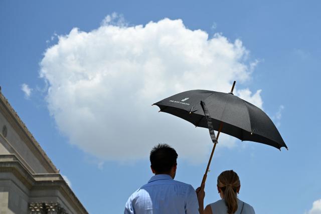 People use an umbrella to stay cool during a heatwave in Washington DC, on July 1, 2026. Tens of millions of Americans sweltered under furnace-like temperatures this week as central and eastern cities hunkered down for a heat wave set to last through the July 4 holiday weekend. Dozens of local temperature records could be broken, the National Weather Service (NWS) warned, with temperatures in many places to surpass 100 degrees Fahrenheit (38 degrees Celsius) and high humidity pushing the heat index as high as 115 degrees. (Photo by Alex WROBLEWSKI / AFP)