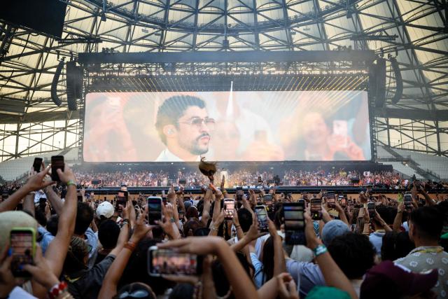 Fans hold up their phones as Puerto Rican singer Bad Bunny performs on stage at the Velodrome Stadium as part of his world tour, in Marseille, southern France, on July 01, 2026. (Photo by CLEMENT MAHOUDEAU / AFP)
