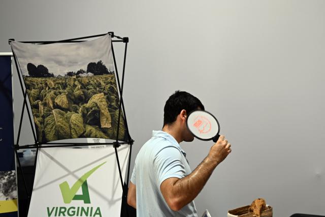 A man uses a fan to stay cool while visiting an exhibit for the state of Virginia at "The Great American State Fair" during a heatwave in Washington, DC, on July 1, 2026. Tens of millions of Americans sweltered under furnace-like temperatures this week as central and eastern cities hunkered down for a heat wave set to last through the July 4 holiday weekend. Dozens of local temperature records could be broken, the National Weather Service (NWS) warned, with temperatures in many places to surpass 100 degrees Fahrenheit (38 degrees Celsius) and high humidity pushing the heat index as high as 115 degrees. (Photo by Alex WROBLEWSKI / AFP)