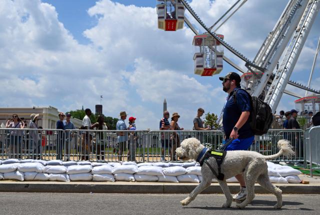 A man walks his dog amid high temperatures while visiting "The Great American State Fair" during a heatwave in Washington, DC, on July 1, 2026. Tens of millions of Americans sweltered under furnace-like temperatures this week as central and eastern cities hunkered down for a heat wave set to last through the July 4 holiday weekend. Dozens of local temperature records could be broken, the National Weather Service (NWS) warned, with temperatures in many places to surpass 100 degrees Fahrenheit (38 degrees Celsius) and high humidity pushing the heat index as high as 115 degrees. (Photo by Alex WROBLEWSKI / AFP)
