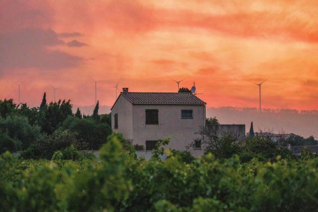 This photograph shows a house under an coloured sky as a wildfire hits Pouzols-Minervois, southwestern of France, on July 1, 2026. (Photo by Idriss Bigou-Gilles / AFP)