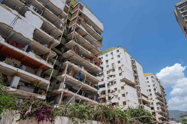 This photograph shows damaged buildings in Playa Grande neighborhood, La Guaira state, Venezuela, on July 1, 2026, following the June 24 twin earthquakes. Tens of thousands of people urgently need food and shelter in Venezuela due to the devastation from two huge earthquakes that killed more than 1,700 and injured 5,000, the UN said on June 30, 2026, as doctors warned of potential outbreaks of disease. (Photo by Miguel MEDINA / POOL / AFP)