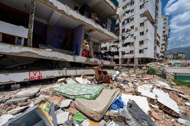This photograph shows a damaged building with debris scattered in the foreground in Playa Grande neighborhood, La Guaira state, Venezuela, on July 1, 2026, following the June 24 twin earthquakes. Tens of thousands of people urgently need food and shelter in Venezuela due to the devastation from two huge earthquakes that killed more than 1,700 and injured 5,000, the UN said on June 30, 2026, as doctors warned of potential outbreaks of disease. (Photo by Miguel MEDINA / POOL / AFP)