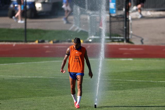 France's defender #02 Malo Gusto walks past a water sprinkler in a training session at Bentley University in Waltham, near Boston, on July 1, 2026, during the 2026 World Cup football tournament. (Photo by FRANCK FIFE / AFP)