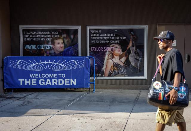 A person walks by a poster featuring an image and quote from US singer-songwriter Taylor Swift outside Madison Square Garden in New York on July 1, 2026. Increasing signs point to a mega-bash for the A-list celebrity couple Taylor Swift and Travis Kelce at Madison Square Garden this week. Rumors have run rampant for weeks that the 36-year-old pop superstar and the three-time NFL Super Bowl winner, both 36, could wed at the storied sports arena, home to the New York Knicks, the newly crowned NBA champions. (Photo by kena betancur / AFP)