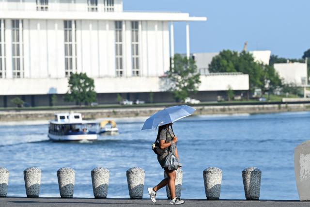 A person uses an umbrella to stay cool while walking along the Potomac River during a heatwave in Washington, DC, on July 1, 2026. Tens of millions of Americans sweltered under furnace-like temperatures this week as central and eastern cities hunkered down for a heat wave set to last through the July 4 holiday weekend. Dozens of local temperature records could be broken, the National Weather Service (NWS) warned, with temperatures in many places to surpass 100 degrees Fahrenheit (38 degrees Celsius) and high humidity pushing the heat index as high as 115 degrees. (Photo by Alex WROBLEWSKI / AFP)