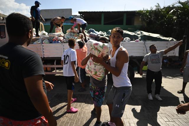 Residents carry packages of aid in Maiquetia, La Guaira State, Venezuela on July 1, 2026, following the June 24 twin earthquakes. Hope of finding more survivors faded on July 1 as Venezuela marked a week since twin earthquakes killed almost 2,300 people, while many who lived through the disaster were running desperately short on food. (Photo by Juan BARRETO / AFP)