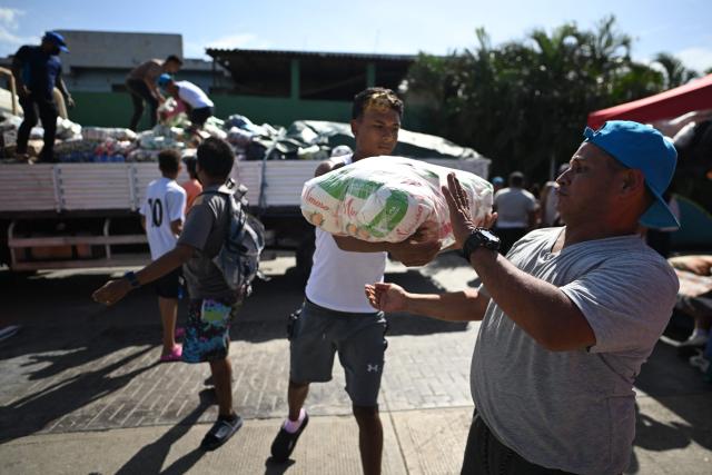 Residents carry packages of aid in Maiquetia, La Guaira State, Venezuela, on July 1, 2026, following the June 24 twin earthquakes. Hope of finding more survivors faded on July 1 as Venezuela marked a week since twin earthquakes killed almost 2,300 people, while many who lived through the disaster were running desperately short on food. (Photo by Juan BARRETO / AFP)