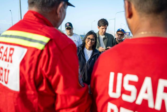 Venezuela's interim President Delcy Rodriguez talks with members of a USAR team from the General Corps of Volunteer Firefighters of Peru during a visit to a temporary camp of the French Civil Security in La Guaira, La Guaira state, on July 1, 2026, following the June 24 twin earthquakes in Venezuela. Hope of finding more survivors faded on July 1 as Venezuela marked a week since twin earthquakes killed almost 2,300 people, while many who lived through the disaster were running desperately short on food. (Photo by Miguel MEDINA / POOL / AFP)