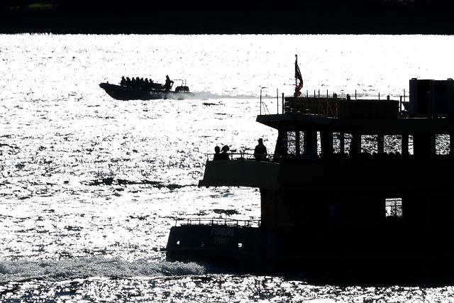 Passengers can be seen aboard a ferry as a speedboat passes behind on Sydney Harbour on a winter’s day in Sydney on July 2, 2026. (Photo by DAVID GRAY / AFP)