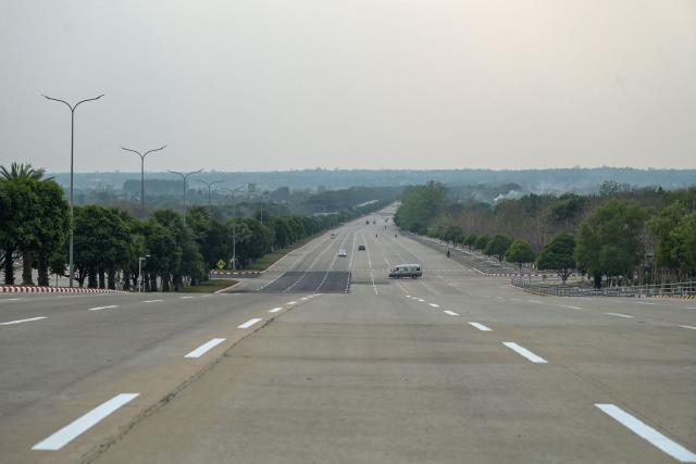(FILES) A car is seen in the distance turning on Yaza Htarni Road in Naypyidaw on March 26, 2024. Myanmar's deposed leader is under house arrest in the capital Naypyidaw, according to her captors, but experts say the city is purpose built to guard secrets of the country's closed-ranks rulers. (Photo by AFP)