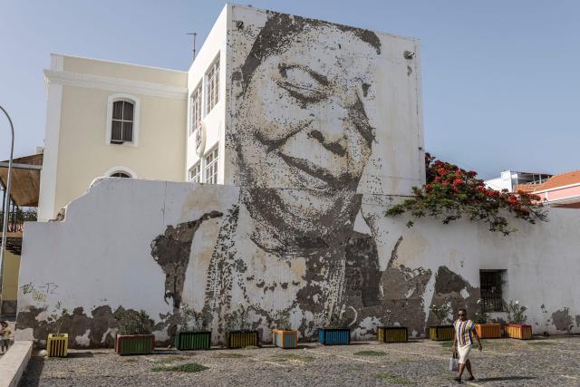 A pedestrian walks past an art installation depicting late Cape Verdean singer Cesaria Evora in Mindelo, on May 27, 2026. Barefoot, arms raised to the sky and overcome with emotion, Ceuzany delivers with her powerful voice the flagship song from her latest album dedicated to the fight against domestic violence, sending shivers through the audience packed into a bar in Mindelo, on the island of Sгo Vicente.
She is compared to the great Cesбria Йvora, the “barefoot diva” who introduced two traditional Cape Verdean music genres to the world: morna (soft, nostalgic melodies) and coladeira (faster-paced rhythm). (Photo by PATRICK MEINHARDT / AFP)