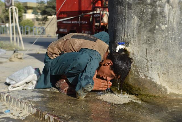 An Afghan boy cools his head under a road-side water tap in Mazar-i-Sharif on July 1, 2026. (Photo by Atif Aryan / AFP)