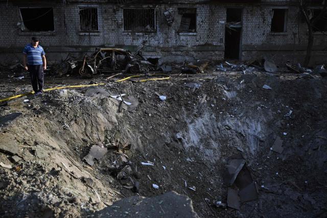 A local resident examines a crater outside a damaged residential building following missile strikes on the Ukrainian capital of Kyiv on July 2, 2026, amid the Russian invasion of Ukraine. Russian missile and drone strikes rocked Kyiv early on July 2, killing at least eight people and wounding dozens, after President Volodymyr Zelensky warned that Moscow was preparing a "massive attack". (Photo by Genya Savilov / AFP)