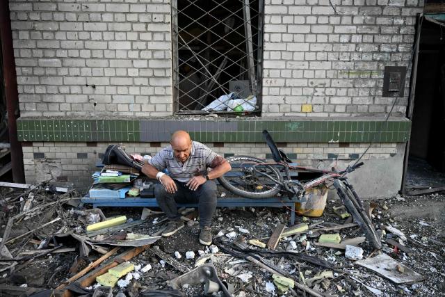 A local resident sits outside a residential building damaged following missile strikes on the Ukrainian capital of Kyiv on July 2, 2026, amid the Russian invasion in Ukraine. Russian missile and drone strikes rocked Kyiv early on July 2, killing at least eight people and wounding dozens, after President Volodymyr Zelensky warned that Moscow was preparing a "massive attack". (Photo by Genya Savilov / AFP)