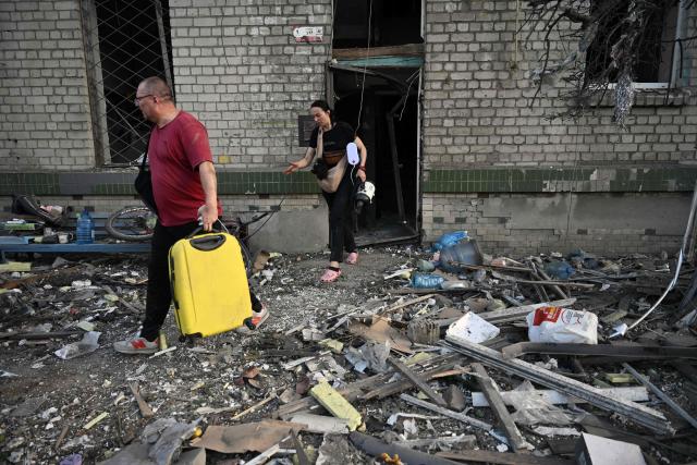Local residents carry their belongings as they leave their residential building damaged following missile strikes on the Ukrainian capital of Kyiv on July 2, 2026, amid the Russian invasion in Ukraine. Russian missile and drone strikes rocked Kyiv early on July 2, killing at least eight people and wounding dozens, after President Volodymyr Zelensky warned that Moscow was preparing a "massive attack". (Photo by Genya Savilov / AFP)