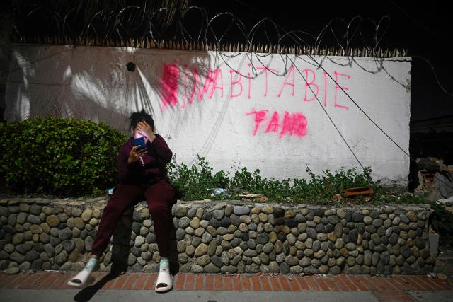 A local resident sits near a wall spray-painted with the word "uninhabitable" in the Los Corales neighbourhood of Caraballeda, La Guaira State, Venezuela on July 1, 2026, following the June 24 twin earthquakes. Hope of finding more survivors faded on July 1 as Venezuela marked a week since twin earthquakes killed almost 2,300 people, while many who lived through the disaster were running desperately short on food. (Photo by Federico PARRA / AFP)