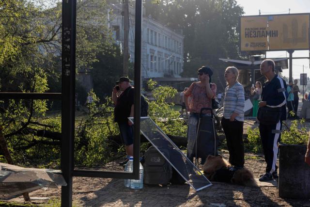 People stand near a damaged bus stop next to a residential building damaged following a Russian air attack on the Ukrainian capital of Kyiv on July 2, 2026, amid the Russian invasion in Ukraine. Russian missile and drone strikes rocked Kyiv early on July 2, killing at least eight people and wounding dozens, after President Volodymyr Zelensky warned that Moscow was preparing a "massive attack". (Photo by Tetiana DZHAFAROVA / AFP)