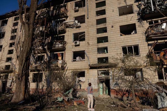 A woman looks at a residential building damaged following a Russian air attack on the Ukrainian capital of Kyiv on July 2, 2026, amid the Russian invasion in Ukraine. Russian missile and drone strikes rocked Kyiv early on July 2, killing at least eight people and wounding dozens, after President Volodymyr Zelensky warned that Moscow was preparing a "massive attack". (Photo by Tetiana DZHAFAROVA / AFP)