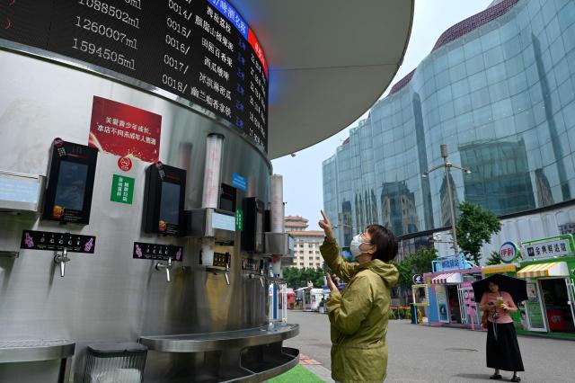 A woman visits a self service beer carousal offering a variety of beer flavours along a business street in Beijing on July 2, 2026. (Photo by WANG Zhao / AFP)