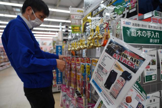 (FILES) A staff member sorts bells next to an advertisement for bear spray at a store in Hanamaki, Iwate prefecture on October 24, 2025. Five people needed hospital treatment in Japan after a man accidentally set off an anti-bear spray in a city-centre post office, reports and officials after the mishap on July 1, 2026, as the country grapples with a sharp rise in maulings. (Photo by Caroline GARDIN / AFP)