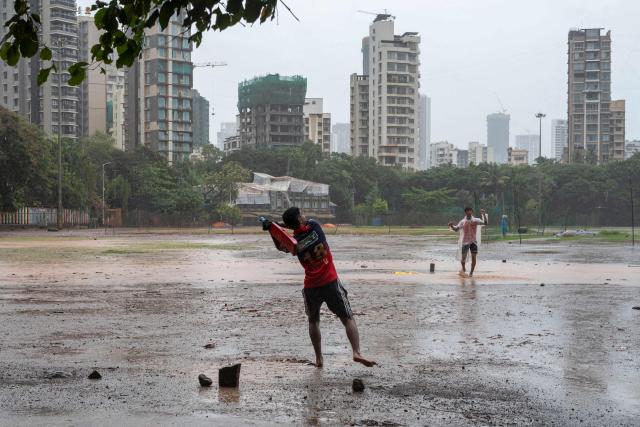 Youths play cricket during rain showers in Mumbai on July 2, 2026. (Photo by Punit PARANJPE / AFP)