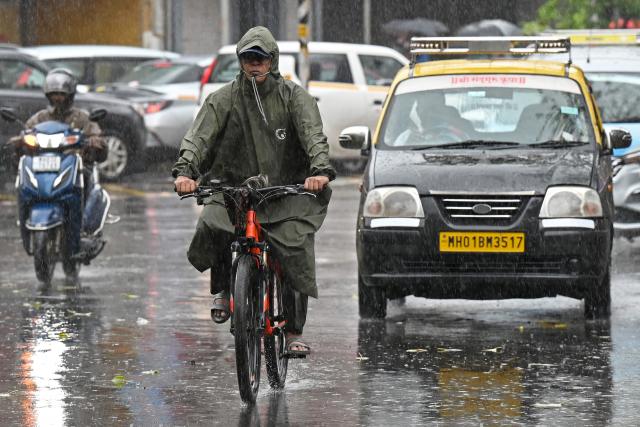 A man rides a bicycle during rain showers in Mumbai on July 2, 2026. (Photo by Punit PARANJPE / AFP)