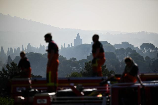 Firefighters look at a wildfire from Pouzols-Minervois, southern France on July 2, 2026. One year after the wildfire in the Corbières massif, the south of France has once again been hit by a large-scale blaze that broke out July 1, 2026 afternoon in the Herault before quickly spreading to the neighboring department of Aude under the combined effect of drought and wind, and is being fought by hundreds of firefighters. (Photo by Lionel BONAVENTURE / AFP)
