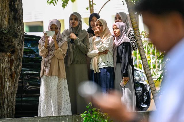 Women watch as a couple who allegedly had sexual intercourse on a TikTok livestream receive a caning as punishment under sharia law in Banda Aceh on July 2, 2026. (Photo by CHAIDEER MAHYUDDIN / AFP)